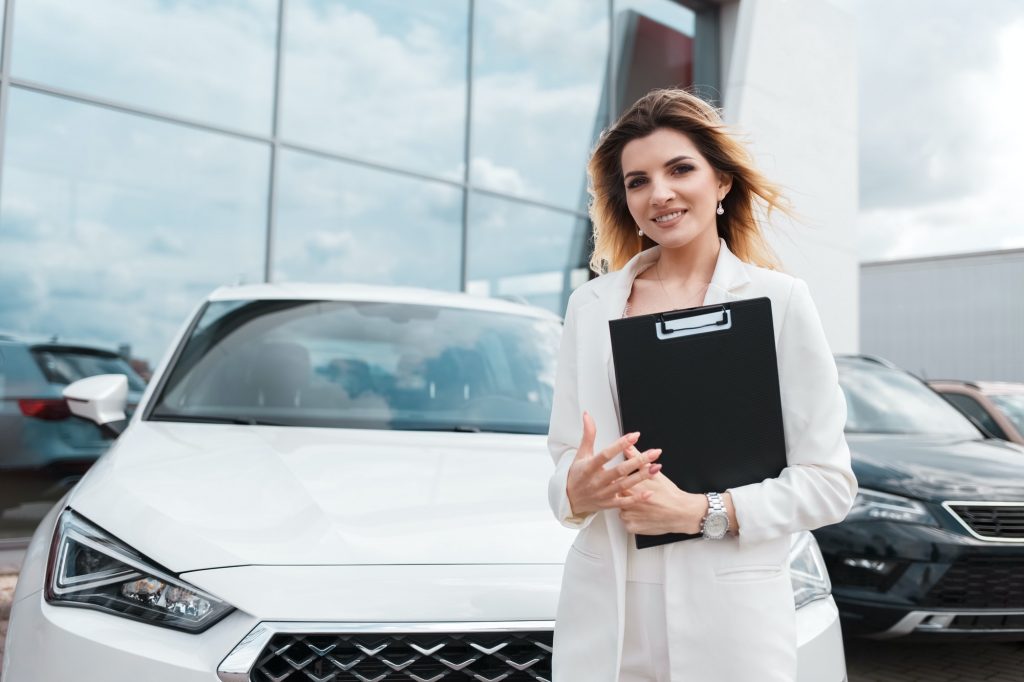 Elegant female car dealership representative in the background of dealer office